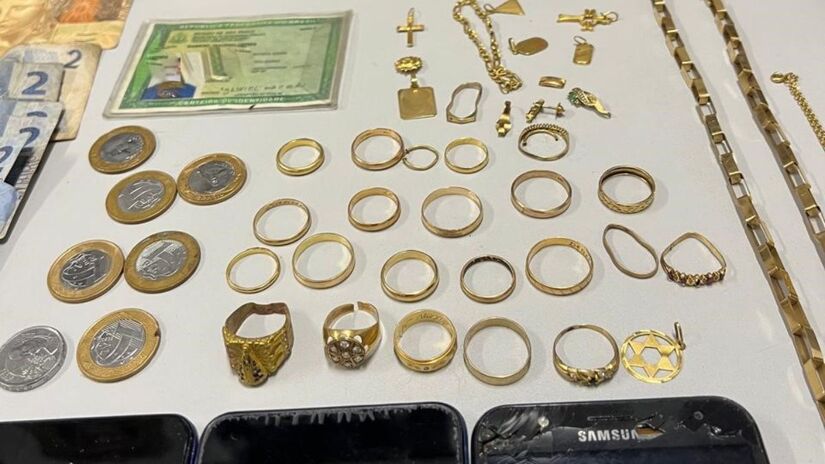 Dezessete alianças, 19 correntes de ouro, 10 pingentes, 05 anéis, 4 pulseiras, 3 brincos, 4 pedaços de ouro, uma balança de precisão, uma caixa de joias, cinco celulares. Crédito: Polícia Civil/SP