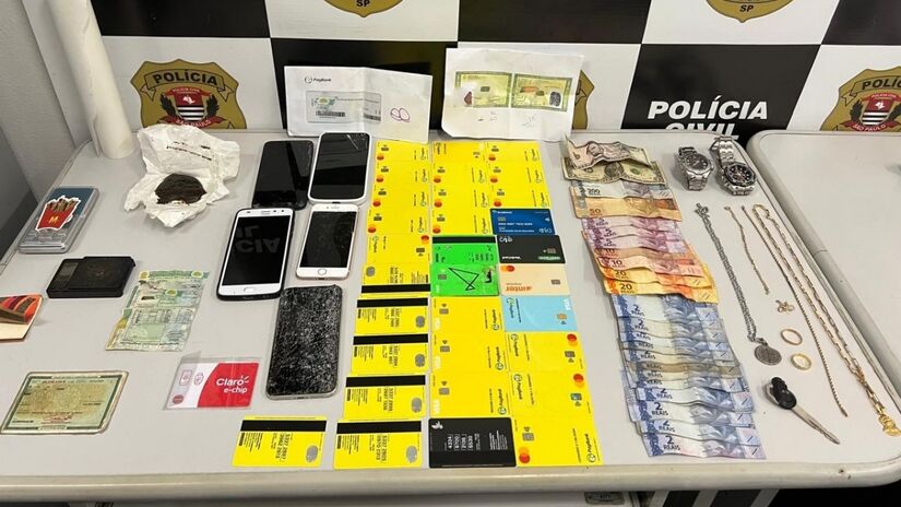Trinta e dois cartões bancários em nome de terceiros, 21 gramas da droga sintética ICE, duas balanças de precisão, R$ 375,00 em espécie, USD 6,00, além de diversas joias. Créditos: Polícia Civil SP