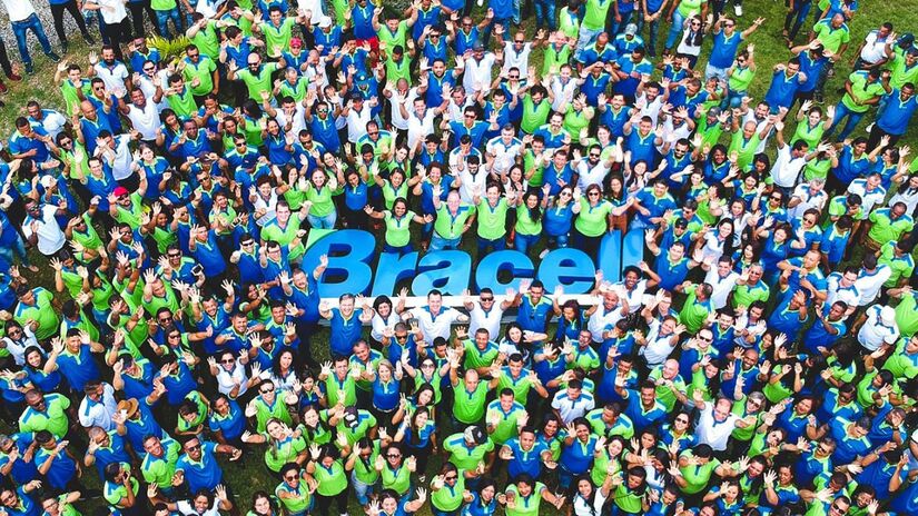 Equipe da Bracell posa em frente à placa da empresa, simbolizando o trabalho colaborativo e o compromisso com a produção e segurança. Créditos: Bracell.
