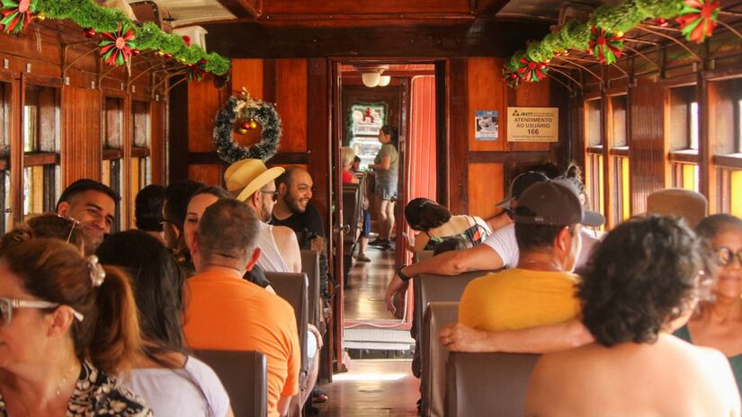 Dentro dos vagões históricos, a decoração especial e as músicas natalinas transformam o passeio em uma experiência encantadora/ Reprodução Facebook/Trem Caiçara