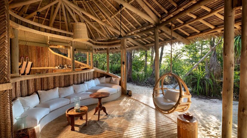 Espaço de convivência aberto para a natureza no andBeyond Mnemba Island, onde o design rústico se integra à tranquilidade da ilha privada em Zanzibar/ andBeyond