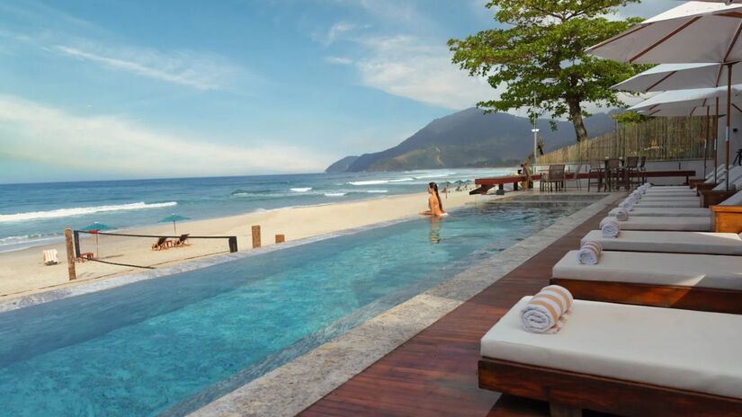 O clima de refúgio é real: hóspedes desfrutam da piscina aquecida com a paisagem da Serra de Maresias ao fundo/ Divulgação