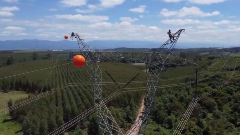 Essas bolas laranjas nos fios de alta tensão são balizas aéreas. Elas existem para que helicópteros e aviões que voam baixo consigam ver os cabos e evitar acidentes/Reprodução/YouTube