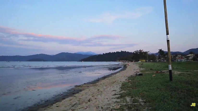 A água tranquila e as marolas discretas revelam áreas onde a lama escura aflora com facilidade / Reprodução/YouTube Jéssica Siqueira