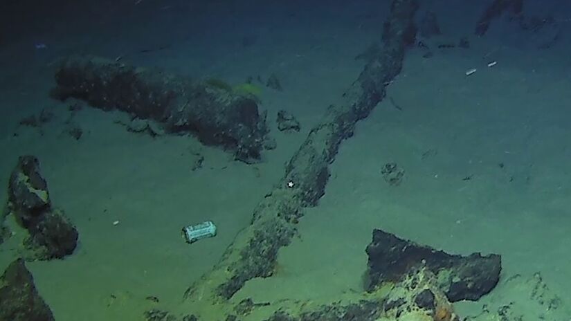 Restos estruturais do navio e fragmentos da carga contrastam com resíduos modernos, lembrando que nem mesmo os abismos marinhos escapam da marca humana/ Reprodução Facebook/Drassm