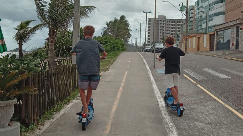 Roberto e o filho Leandro, de S&atilde;o Paulo, tamb&eacute;m estavam, pela primeira vez, andando de patinete na orla da praia (Nayara Martins/DL)