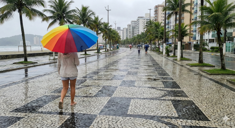 Pedestres se protegem da chuva constante na orla da praia / Gemini