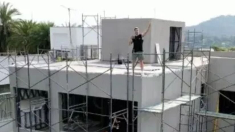 Área externa da casa tem piscina com raia central e deck de madeira em espaço inspirado em resorts/Reprodução