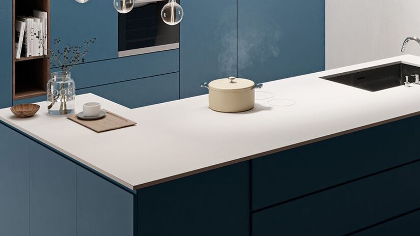 A tecnologia de indução invisível elimina o tradicional recorte no balcão e transforma toda a bancada de porcelanato em uma superfície de cocção funcional e contínua. Na imagem, a panela sobre a pedra ilustra o conceito de "fogão oculto" que virou tendência para 2026. /Divulgação