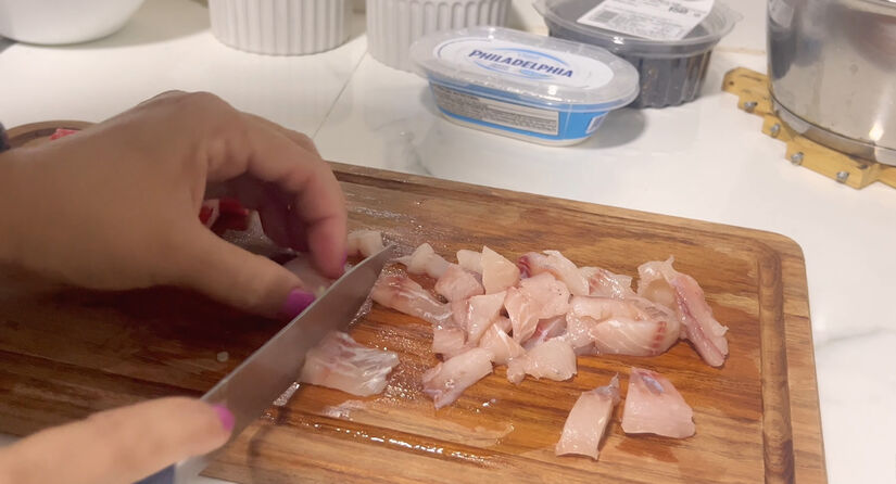 m uma travessa, faça uma camada com a tilápia em cubos, espalhe o cream cheese e cubra com o arroz já frio. Youtube/Receitas Simples e Fáceis/Caprichos do Lar