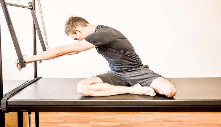 Homem apto fazendo flexões cruzadas durante o treinamento na máquina de  pilates