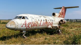 Avião abandonado e enferrujado em área rural, com a inscrição “Água Limpa” na fuselagem.