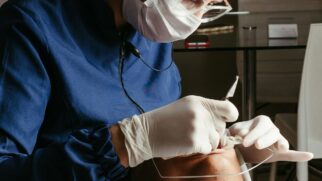 Dentista realiza procedimento na boca de paciente deitado na maca