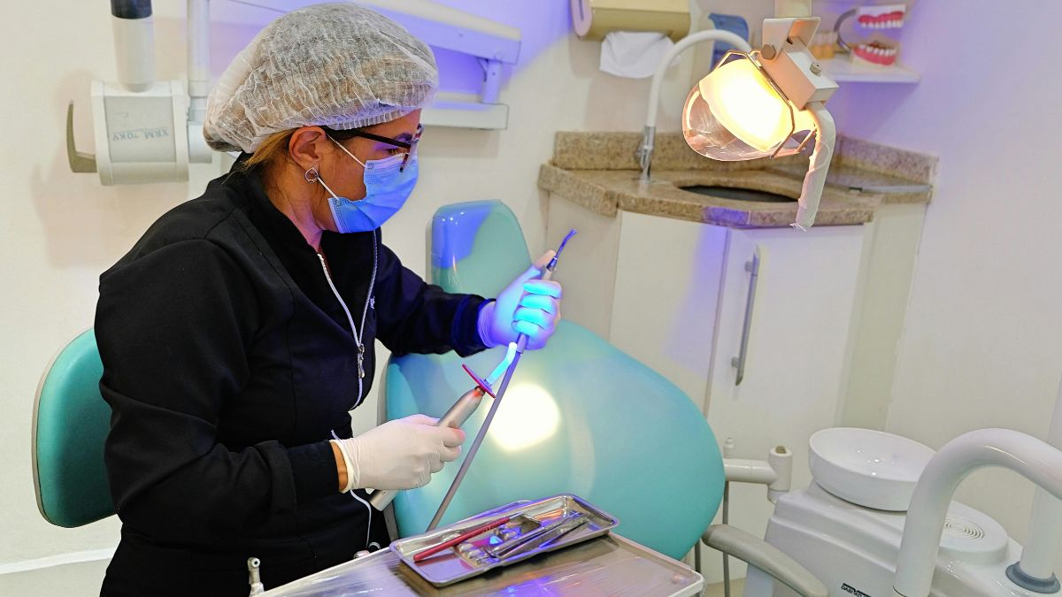 Profissional de odontologia prepara equipamento em consultório antes de atendimento ao paciente