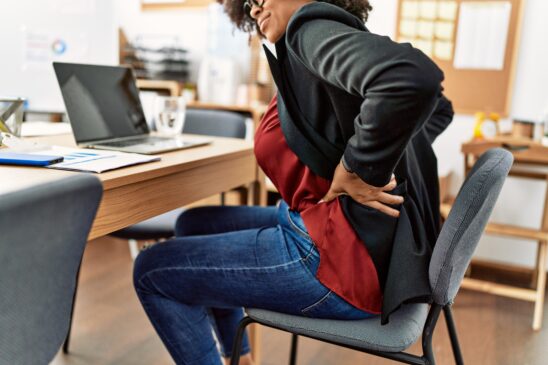 Mulher com dores na costa/Young african american woman suffering for backache working at office