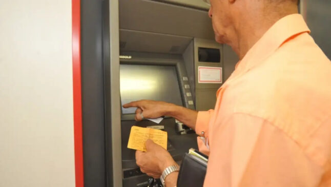 A imagem mostra um homem fazendo operação em Caixa Eletronico