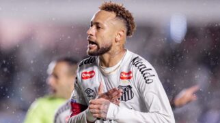 Jogador do Santos FC durante partida sob chuva, usando uniforme branco e faixa de capitão.