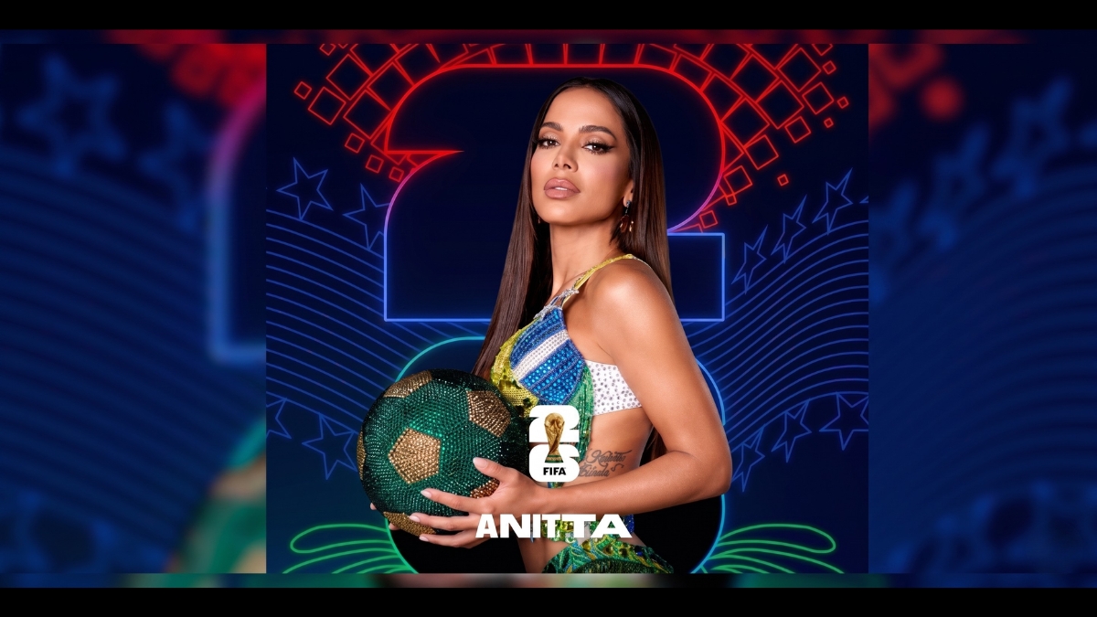 Foto promocional da cantora Anitta segurando uma bola de futebol verde e dourada cravejada de joias, com um fundo neon de estrelas e o logotipo da FIFA 2026