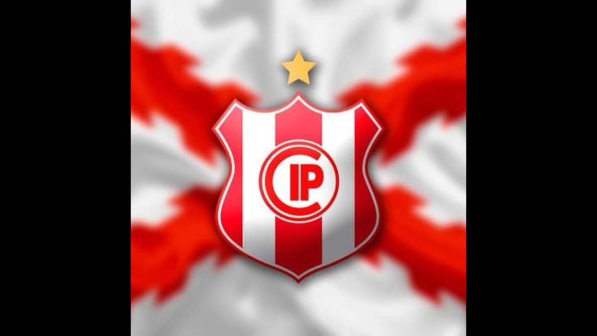 Escudo do Independiente Petrolero em destaque sobre um fundo estilizado com uma vermelha esfumaçada. O brasão tem listras vermelhas e brancas;
