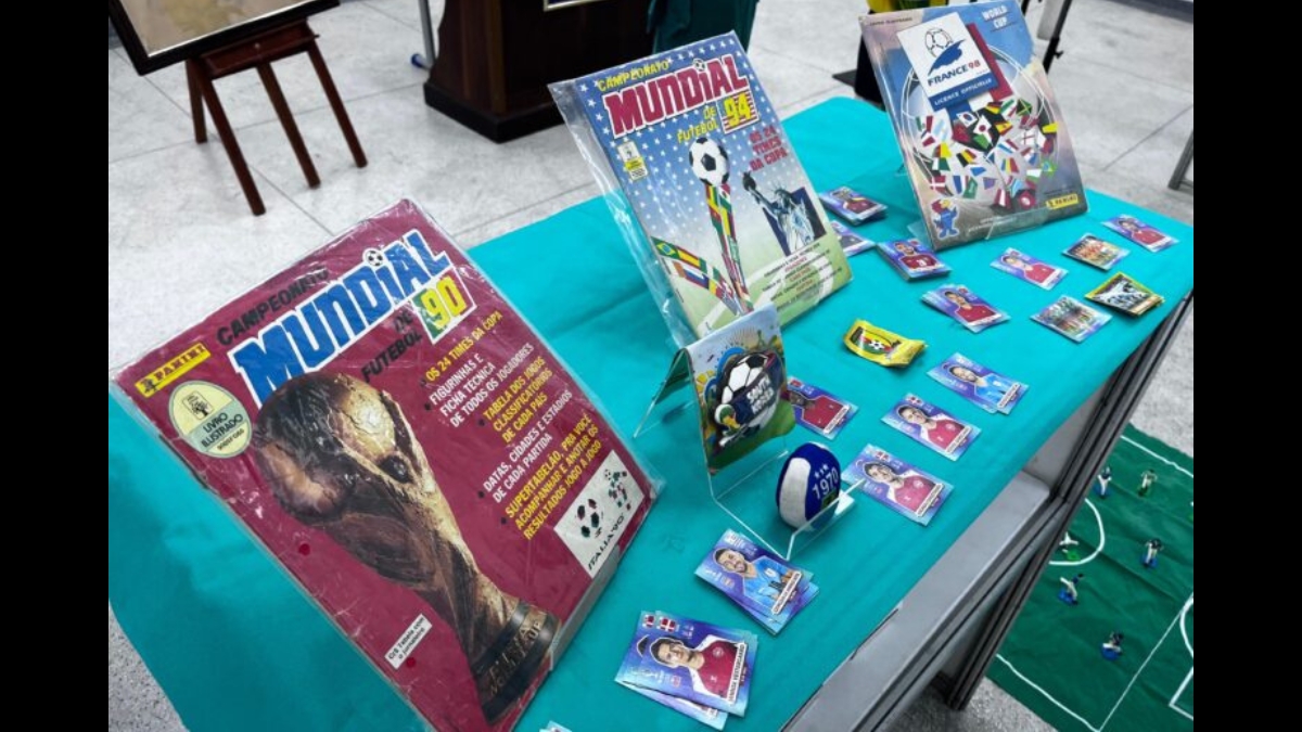 Mesa com álbuns das Copas de 1990 e 1994 e um minicampo de botão.