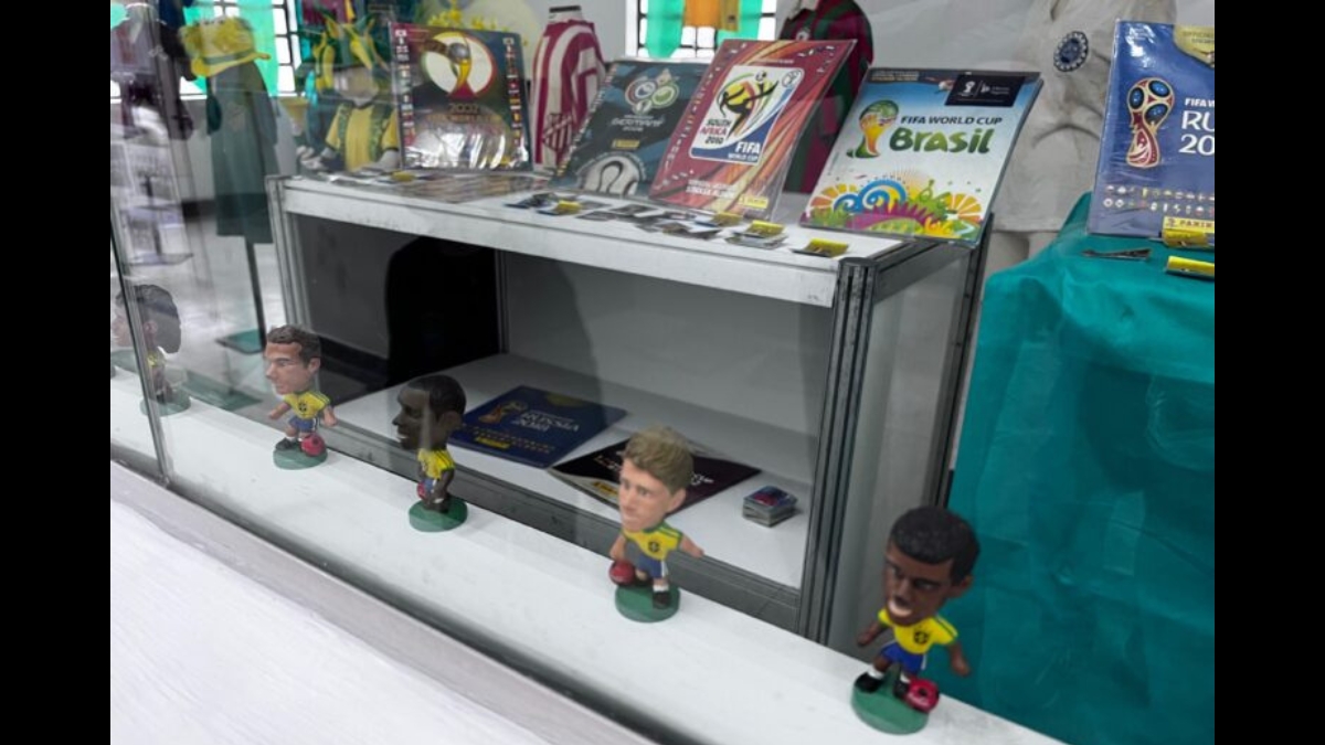 Vitrine com bonecos cabeçudos de jogadores do Brasil e álbuns de Copas.