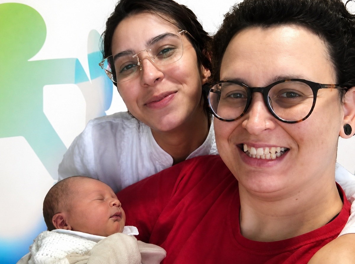 Casal homoafetivo com a filha recém-nascida no colo