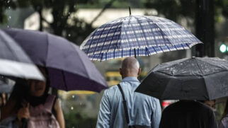 Pessoas usam guarda-chuva na rua após mudança de tempo, com chuva e frio