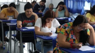 A imagem mostra uma sala durante a prova de concurso publico