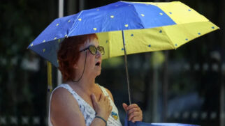 Idosa usa guarda-chuva para se proteger do sol na europa, que vive calor extremo fora de época