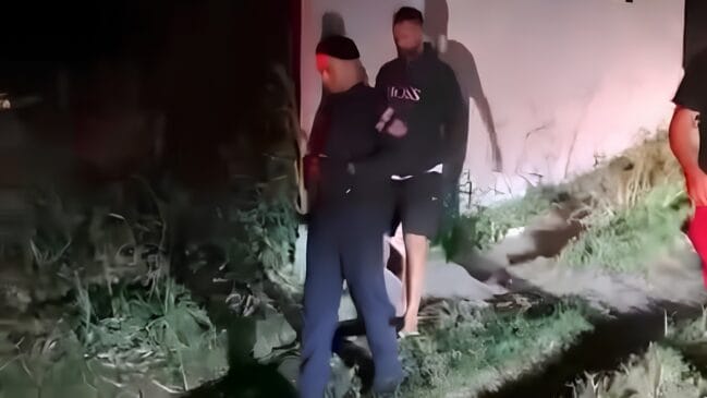 A imagem mostra o goleiro Bruno sendo levado pela polícia militar