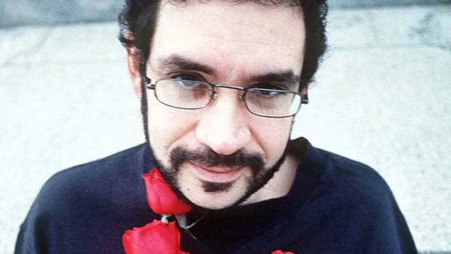 etrato em close-up do cantor Renato Russo, vocalista da Legião Urbana, usando óculos e com rosas vermelhas junto ao peito, ilustrando o significado de L'Avventura e a liberdade