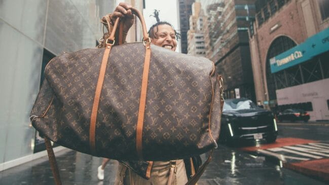 Pessoa segurando e exibindo uma bolsa da Louis Vuitton