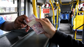 Passageiro paga passagem de ônibus em dinheiro com uma nota de R$ 5