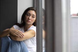 portrait-young-woman-with-low-self-esteem-sitting-by-window-home