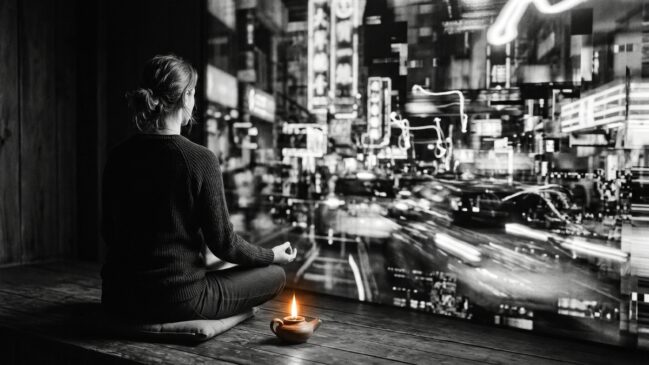 Pessoa em meditação serena ignorando o fundo caótico e barulhento, ilustrando o controle da atenção proposto por Buda.