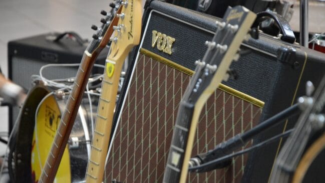 Guitarras elétricas apoiadas ao lado de amplificador em estúdio ou sala de ensaio musical.