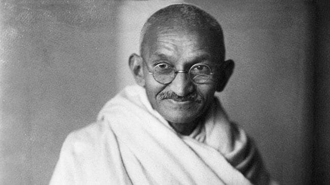 A imagem mais recente mostra Mahatma Gandhi em um retrato histórico em preto e branco, usando óculos redondos e uma veste clara. A fotografia tem um aspecto documental e remete a temas como história, política, filosofia, movimentos sociais ou biografias.