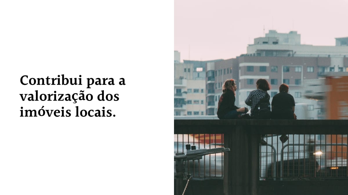 Imagem dividida ao meio. Do lado esquerdo, um fundo branco com a frase em letras pretas: "Contribui para a valorização dos imóveis locais." Do lado direito, uma fotografia de três pessoas sentadas em uma estrutura elevada de costas, observando edifícios urbanos ao fundo.