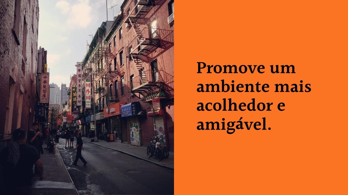 Imagem dividida ao meio. Do lado esquerdo, uma rua de bairro comercial com pedestres caminhando e prédios com escadas de incêndio. Do lado direito, um fundo laranja com a frase em letras pretas: "Promove um ambiente mais acolhedor e amigável."