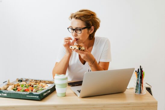 Mulher almoçando na mesa de trabalho