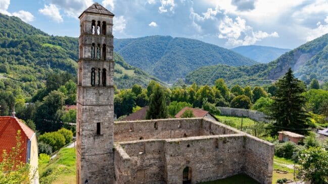 Fotografia horizontal registrando as ruínas de pedra da Igreja de São Lucas e sua torre sineira medieval em Jajce