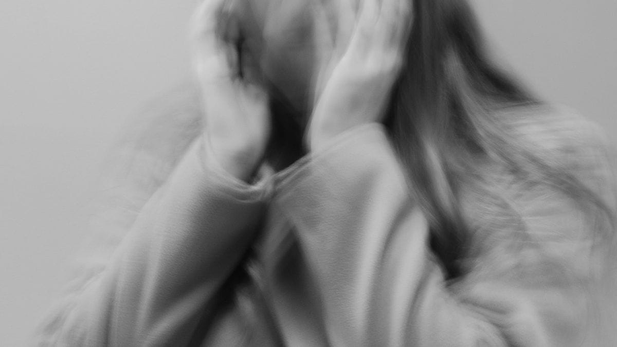 Criança com o rosto tapado por mãos