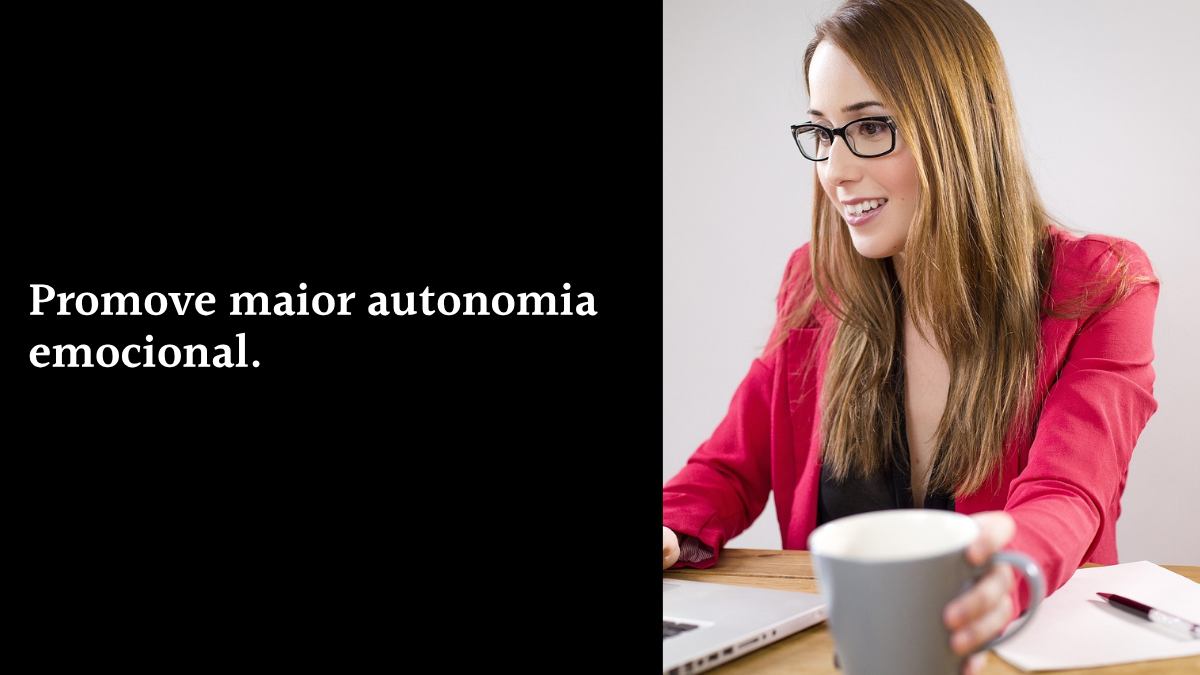 Mulher de negócios sorridente usando óculos e blazer vermelho, trabalhando em seu laptop, ao lado de fundo preto com o texto: "Promove maior autonomia emocional."