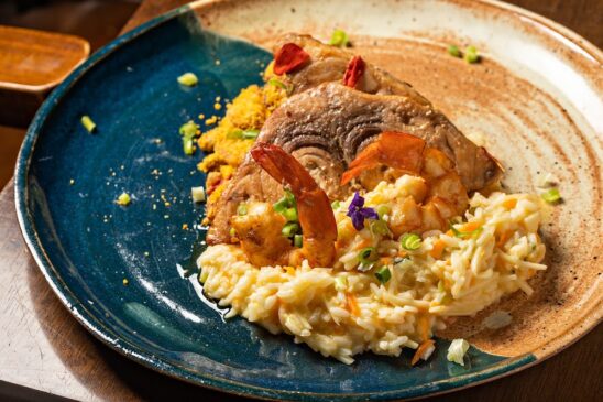 A tradicional meca santista grelhada, que inclui camarão rosa grelhado com risoto de pupunha e farofa de banana, está entre os pratos principais do restaurante
