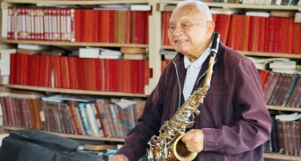 Maestro Sarrafo toca a música "Carinhoso", de Pixinguinha, no saxofone, na sua casa, em Itanhaém