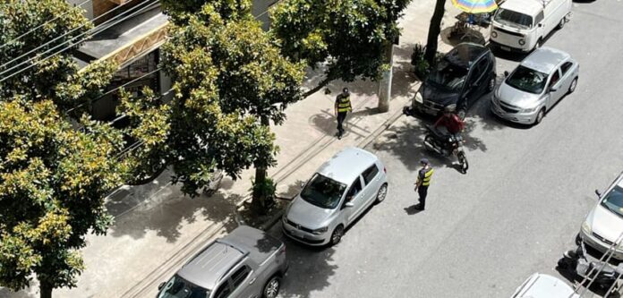 Motociclista levanta a moto ao lado da GCM e do carro que a teria atingido ao estacionar