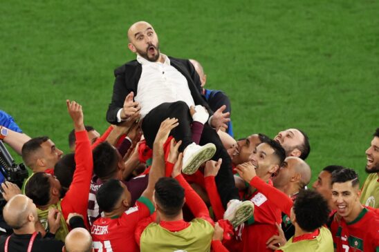 Seleção de Marrocos celebra com seu treinador sua classificação para as Quartas da Copa do Mundo