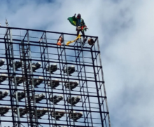 Homem protestou envolto a uma bandeira do Brasil em cima de refletor de estádio