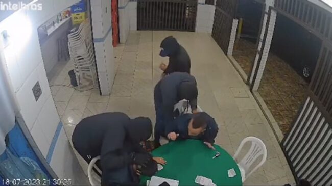 Um dos assaltantes fica o tempo todo com as mãos sobre as cabeças das vítimas e conversando com elas.