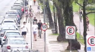 Nas imagens, é possível visualizar dois jovens transitando no calçadão da orla com aparelhos celulares nas mãos.